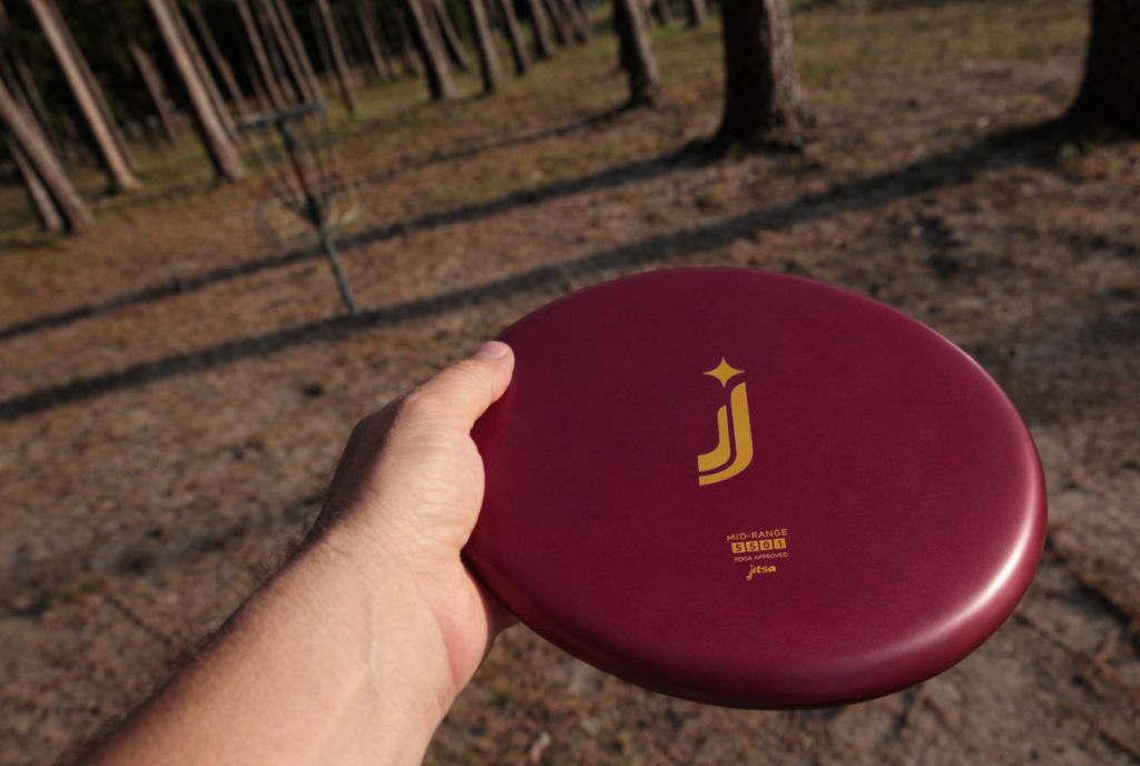Dysk disc golf Mid-Range Jitsa w lesie wśród drzew
