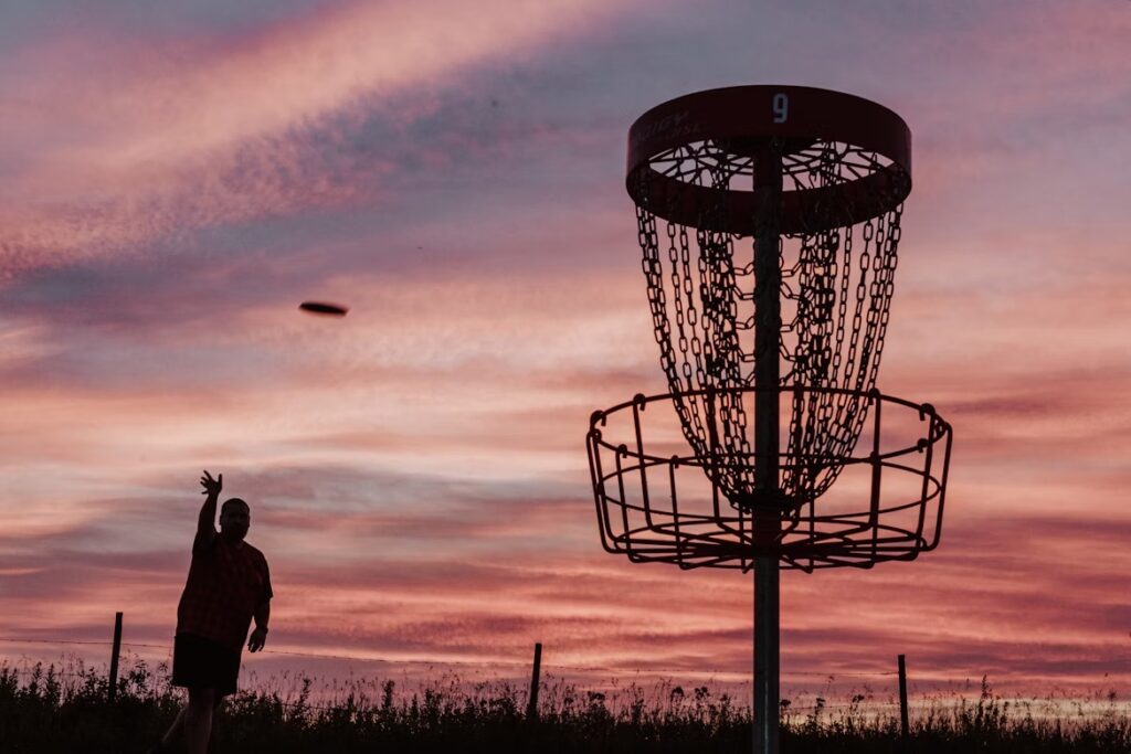 pole disc golf jitsa o zachodzie. gracz disc golf rzucający do kosza.